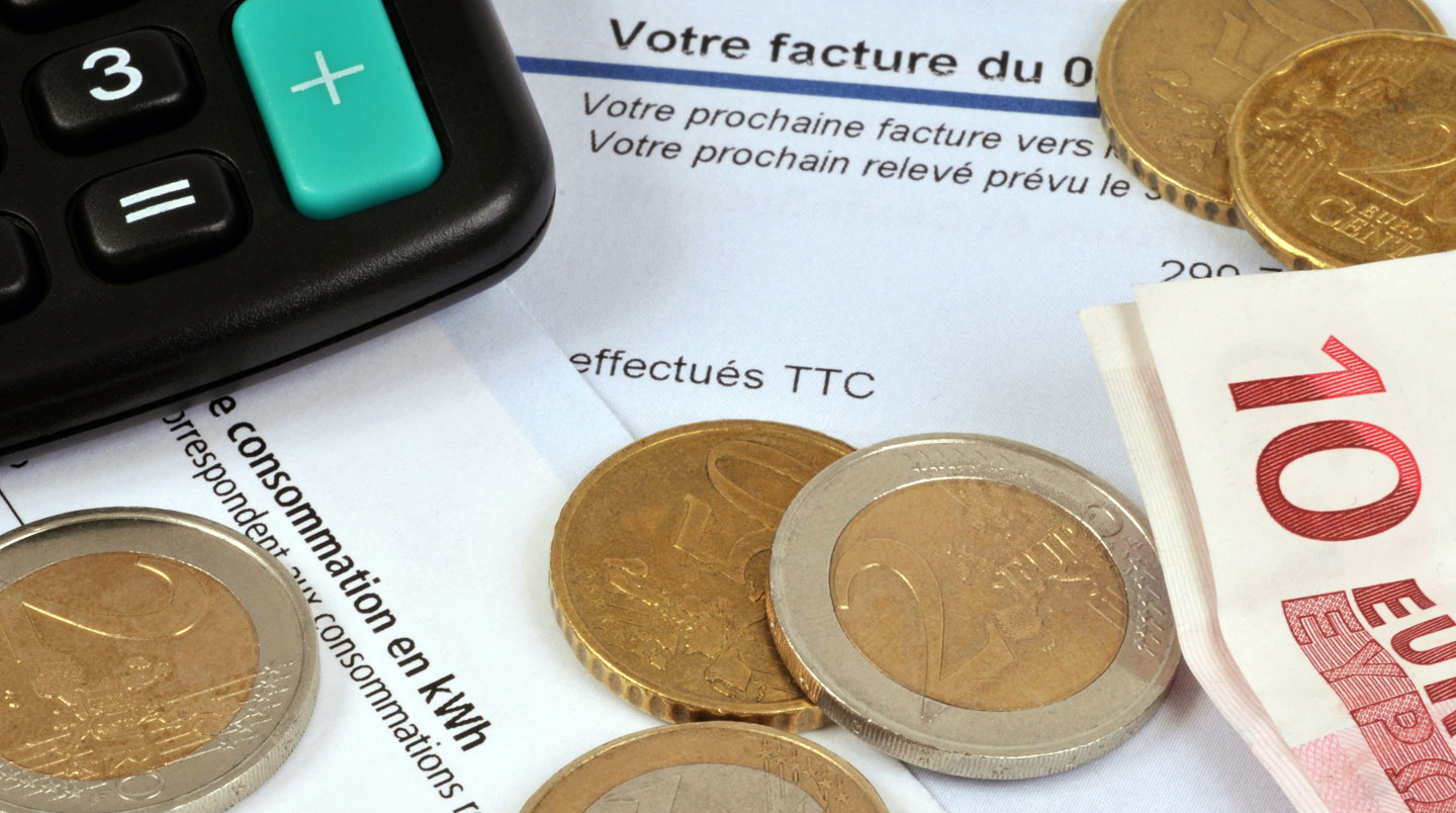 Gros plan sur une facture d'électricité professionnelle avec graphique de consommation visible, texte flouté, main tenant le document en arrière-plan flou